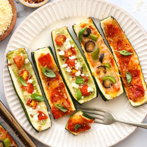 zucchini pizza boats with different toppings on a plate.