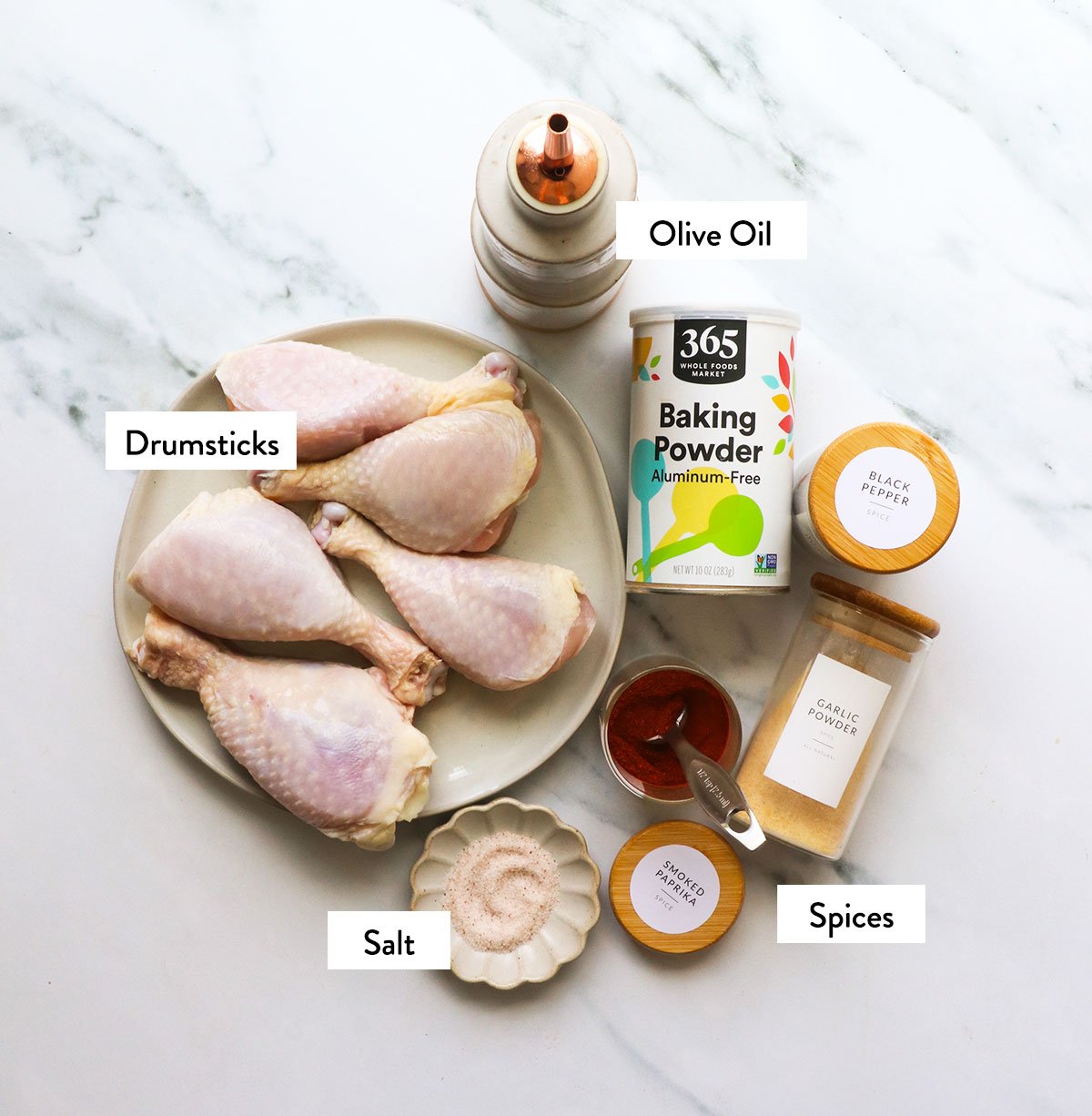 chicken drumsticks, baking powder, spices, and olive oil labeled in bowls.
