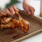 baked drumstick lifted on a wire baking sheet.