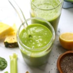 glowing green smoothie served in two glasses with a straw.