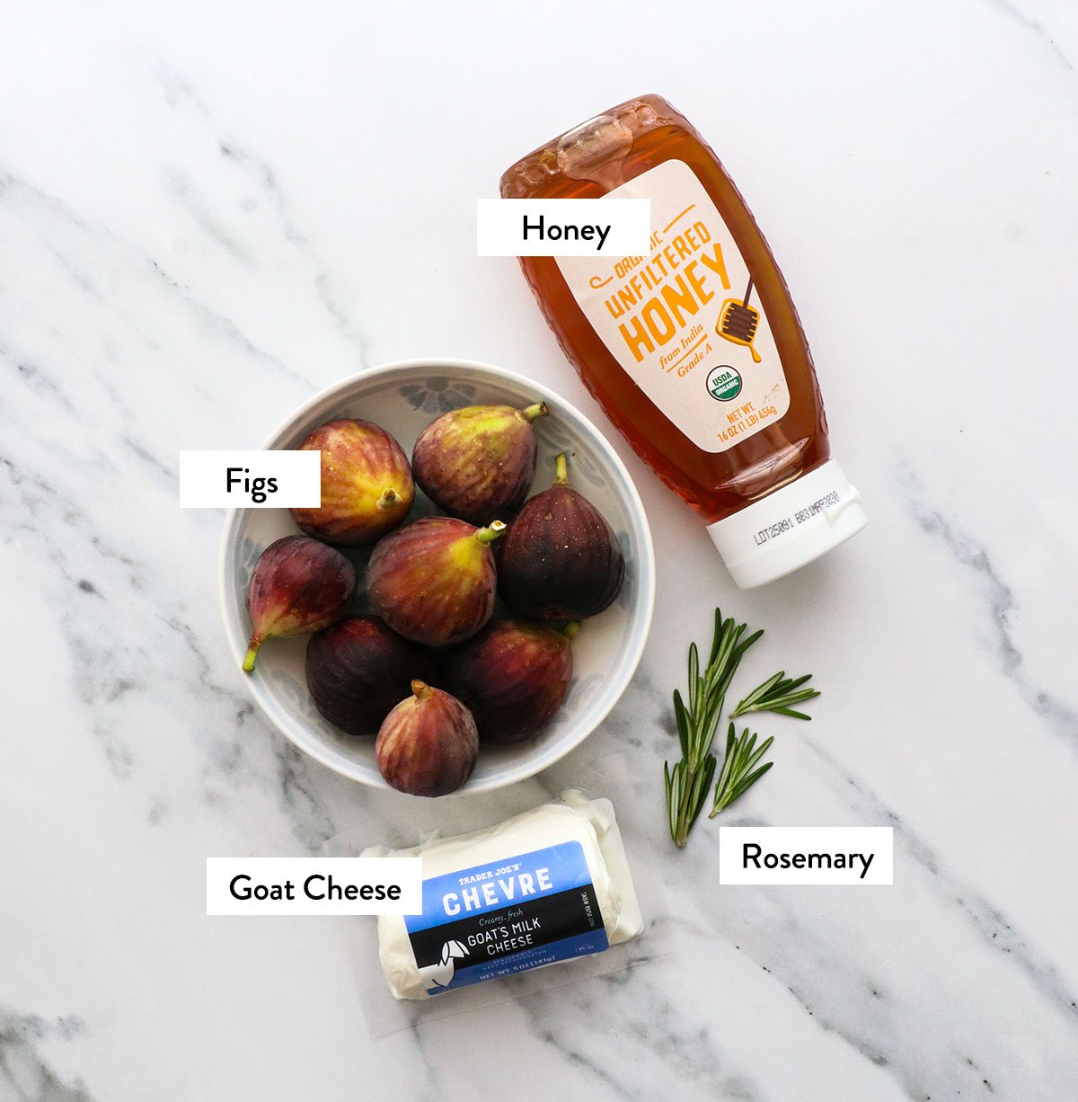 figs, honey, chevre, and rosemary labeled on a white surface. 