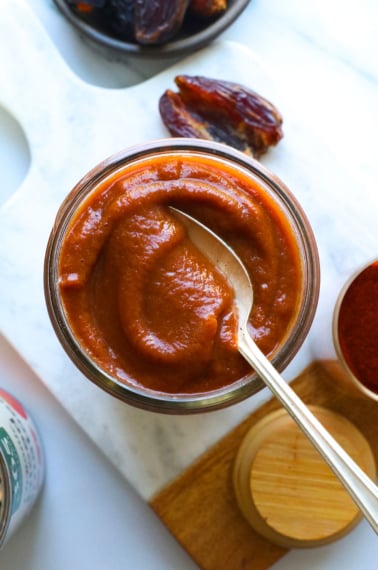 Healthy BBQ sauce in a glass jar with a spoon.