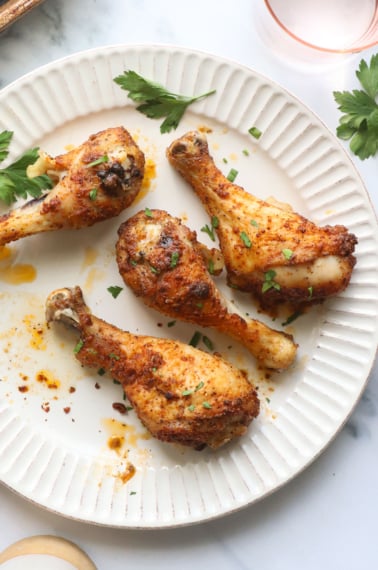 oven baked chicken drumsticks on a white plate for serving.