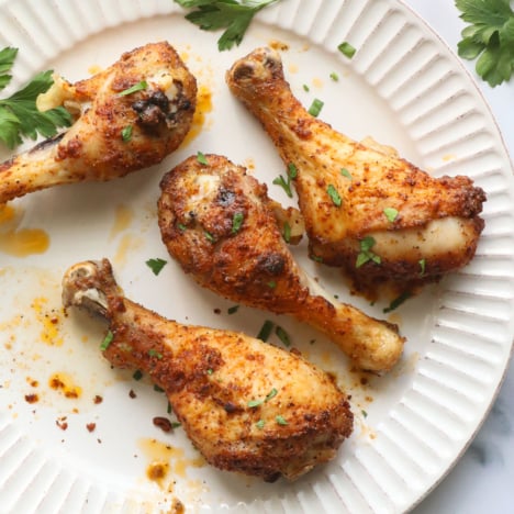 oven baked chicken drumsticks on a white plate for serving.