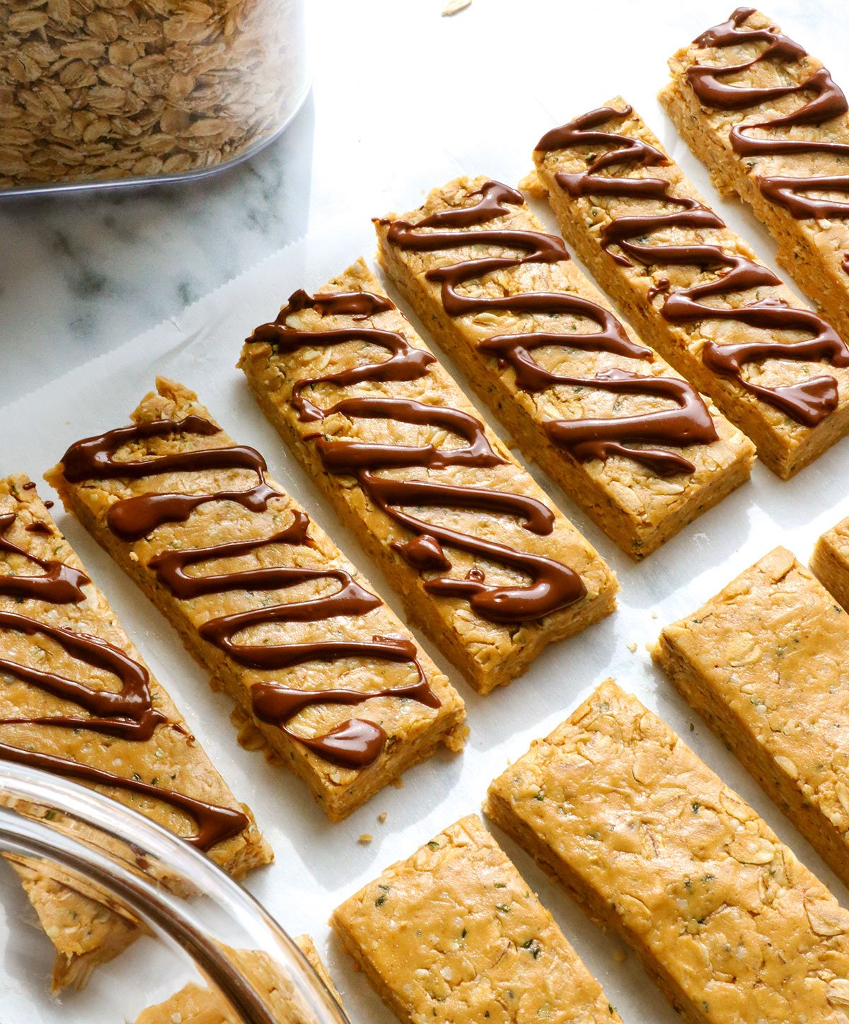 peanut butter protein bars sliced on parchment and topped with chocolate.