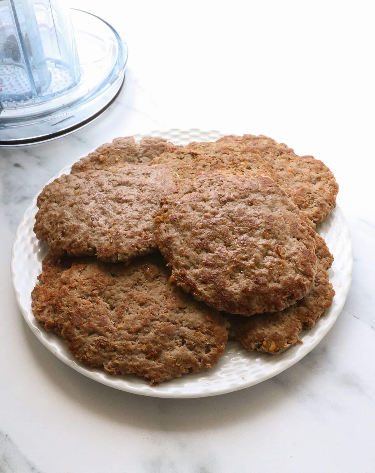 A white plated filled with a stack of healthy cooked burgers.