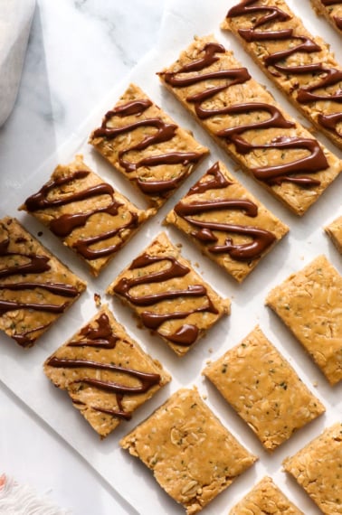 homemade protein granola bars cut into small pieces and some topped with chocolate.