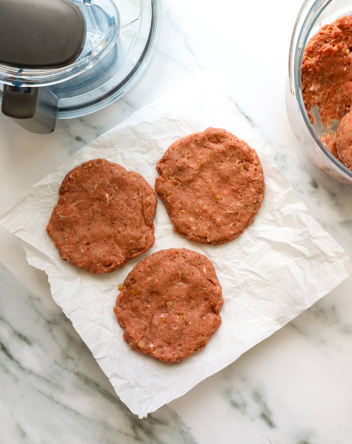 healthy burger patties shaped on a parchment lined plate.