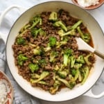 ground beef and broccoli cooked in a white skillet.