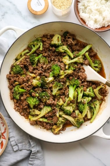 ground beef and broccoli cooked in a white skillet.