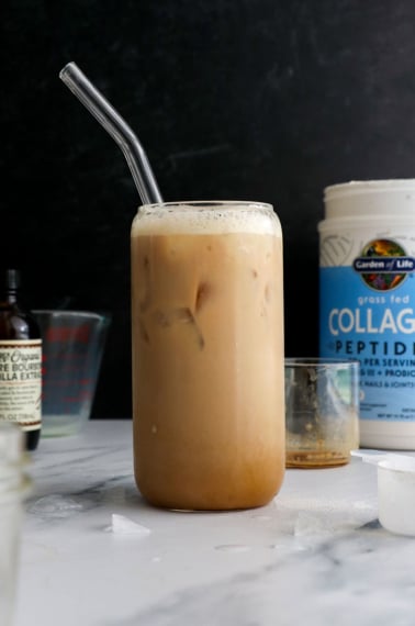 iced protein latte with a glass straw on a black background.