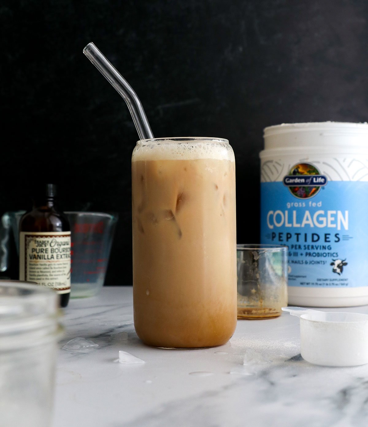 iced protein latte with a glass straw on a black background.