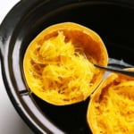 spaghetti squash cooked in a black slow cooker with a fork.