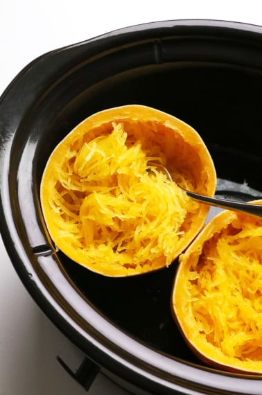 spaghetti squash cooked in a black slow cooker with a fork.