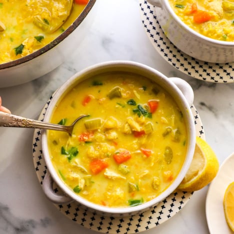 chicken curry soup served in two bowls with a silver spoon.