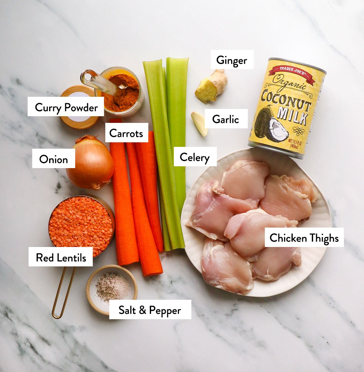 coconut milk, chicken thighs, veggies, red lentils, and spices labeled on a white surface. 