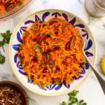 carrot salad with raisins and pecans served in a colorful bowl with a fork.