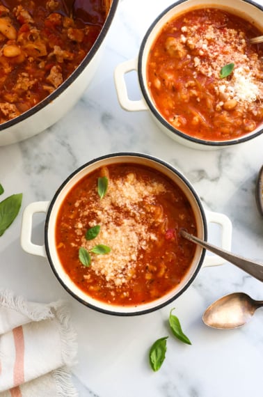 spaghetti squash soup in two bowls with parmesan and basil on top.
