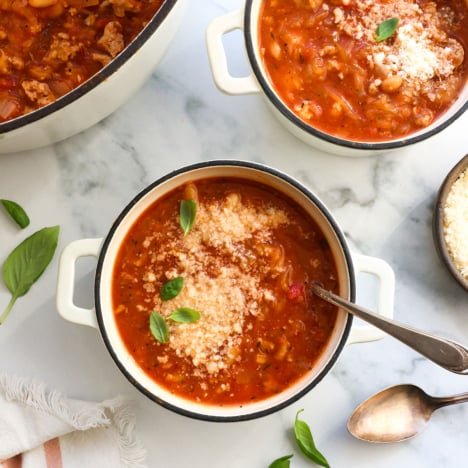 spaghetti squash soup in two bowls with parmesan and basil on top.