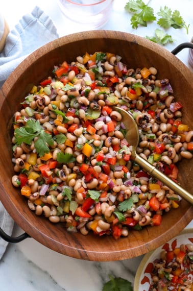 black eyed pea salad served in a wooden salad bowl with a spoon.