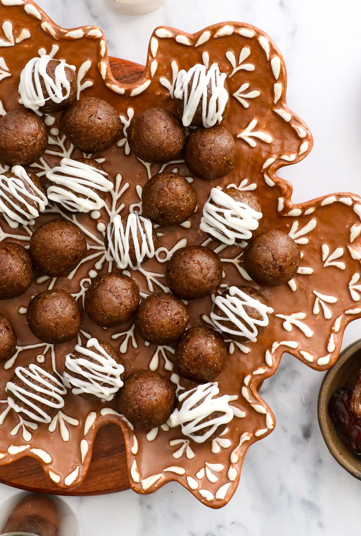 gingerbread energy balls topped with white chocolate on a snowflake plate.