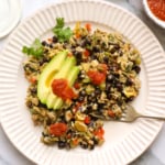 high protein breakfast scramble on a plate topped with avocado slices.