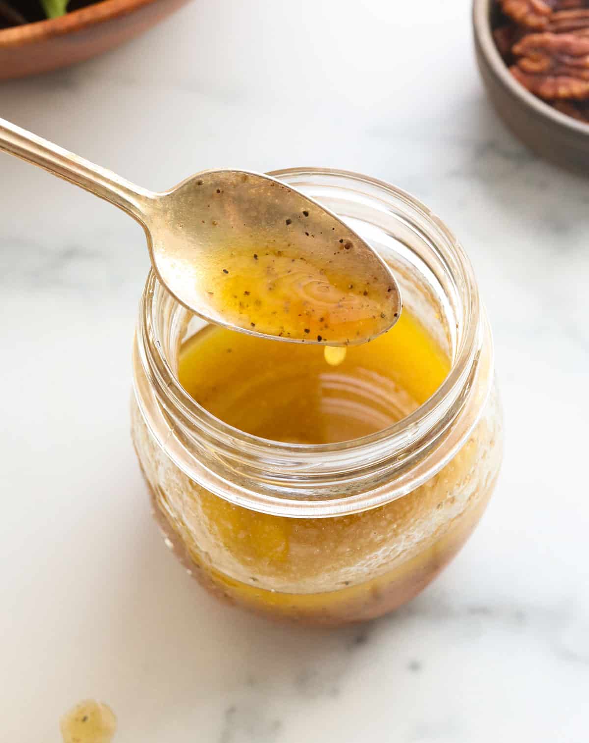 salad dressing stirred with a spoon in a glass jar.