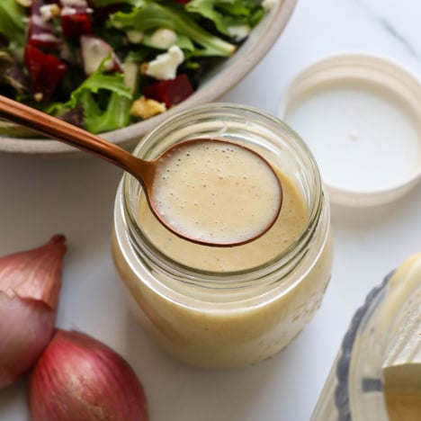 shallot vinagirette on a spoon over a glass jar of dressing.