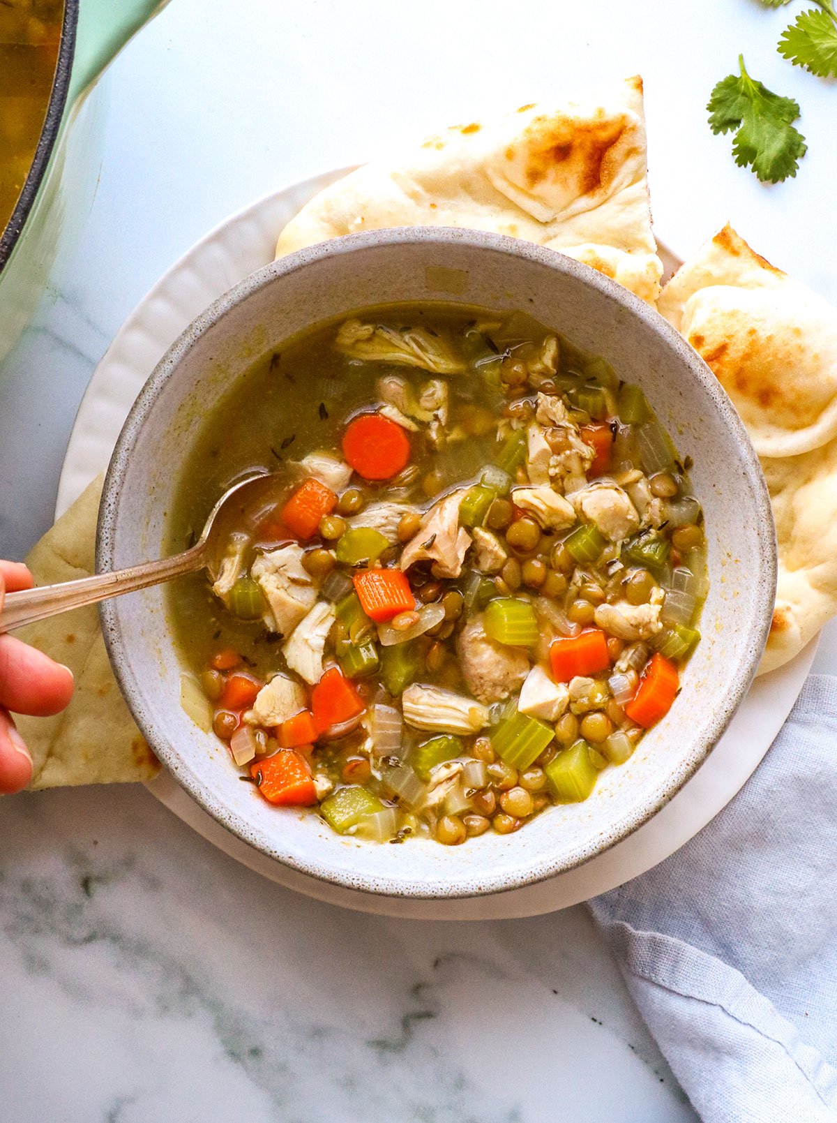 chicken and lentil soup served with bread on the side and a spoon. 