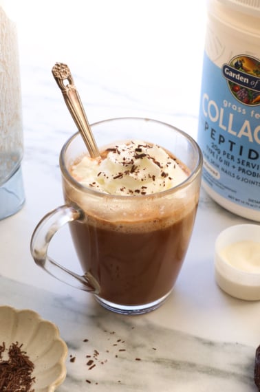 collagen hot chocolate in a glass mug with whipped cream on top.