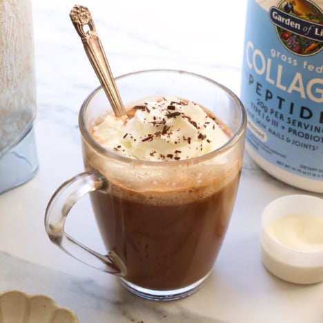 collagen hot chocolate in a glass mug with whipped cream on top.