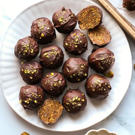 chocolate pistachio balls on a white plate.