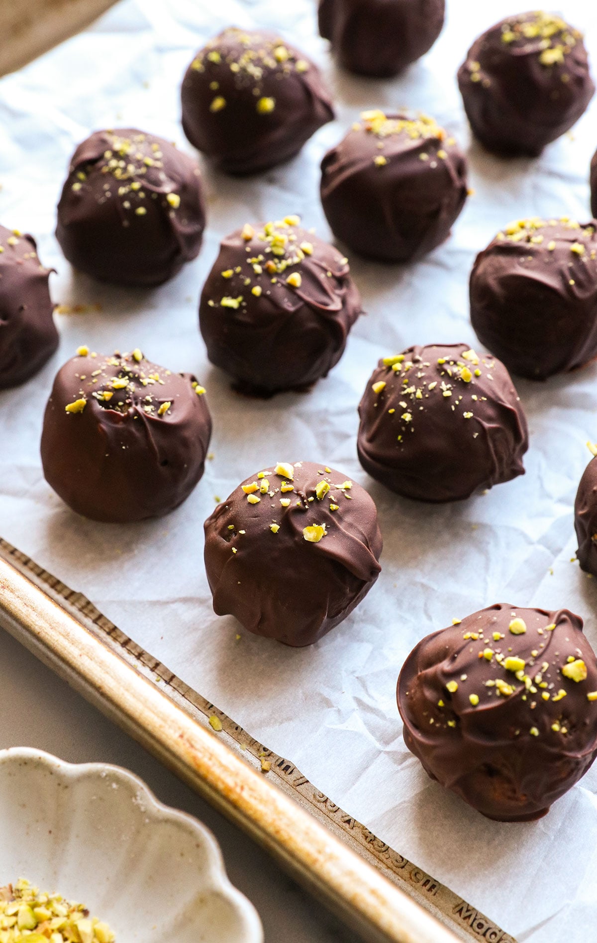 pistachio balls cooled on a pan with parchment paper.