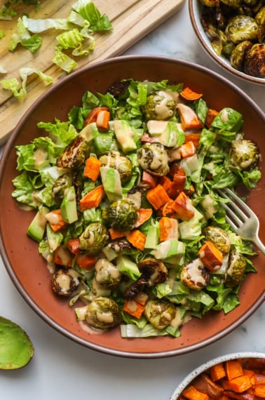 roasted vegetable salad topped with sweet potato, avocado, brussels sprouts and dressing.