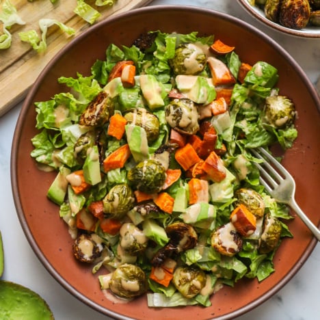 roasted vegetable salad topped with sweet potato, avocado, brussels sprouts and dressing.