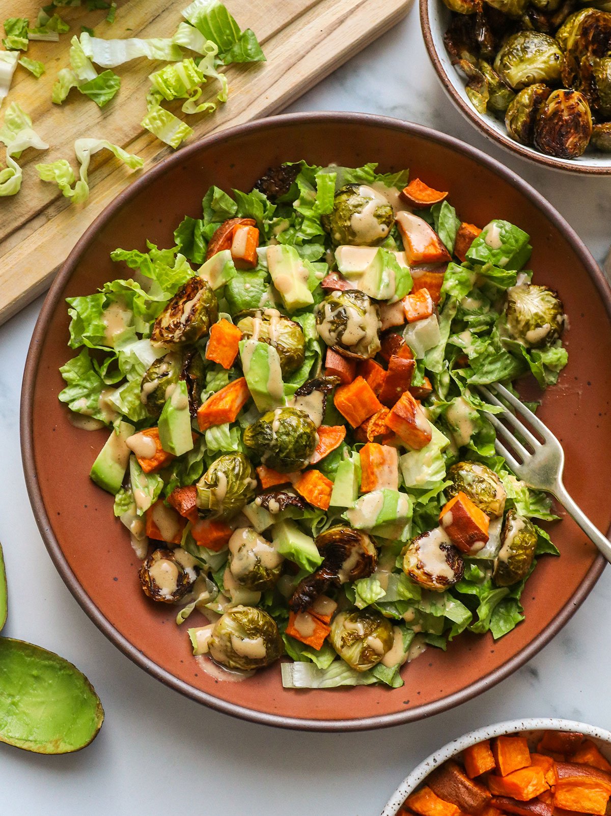roasted vegetable salad topped with sweet potato, avocado, brussels sprouts and dressing. 