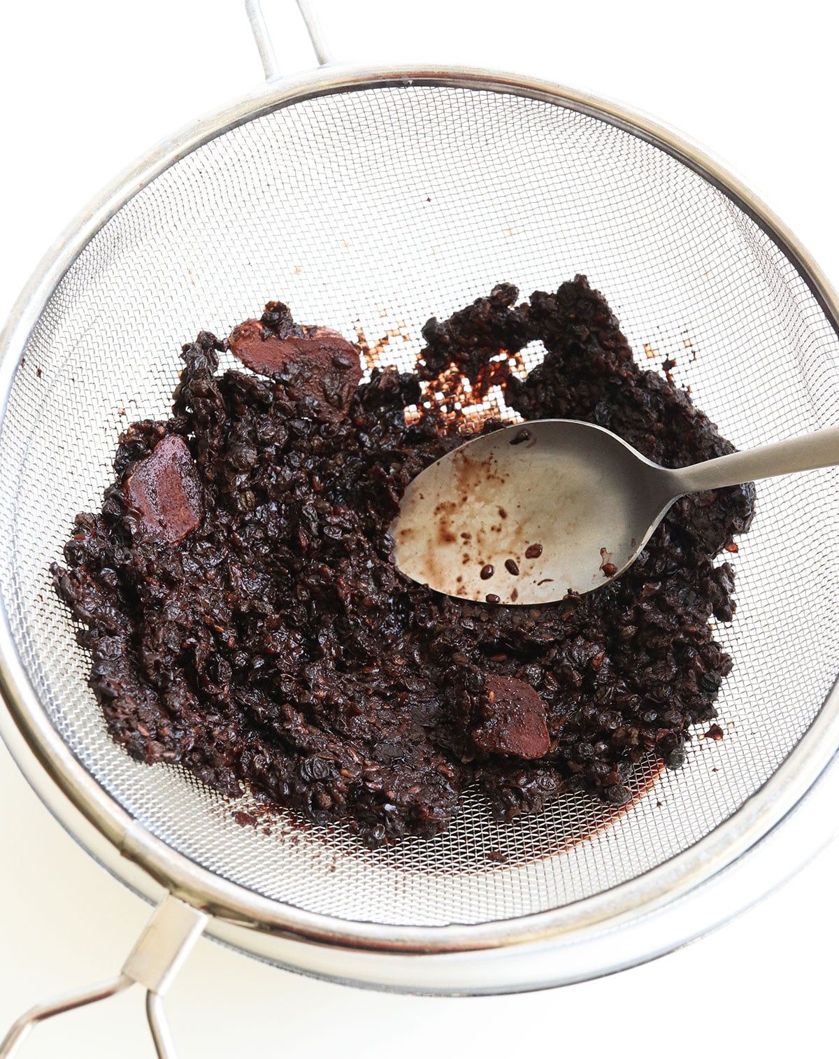 elderberries pressed in a fine mesh strainer to remove juices.