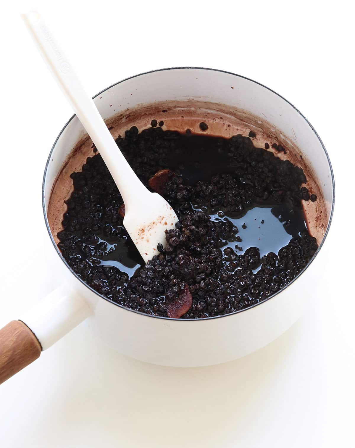liquid reduced by half in the pot of elderberries with a spatula for stirring.