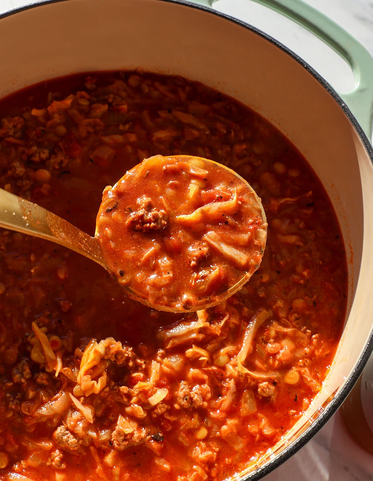 stuffed cabbage soup lifted up on a ladle from the soup pot.