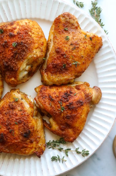 bone-in chicken thighs on a plate with fresh thyme