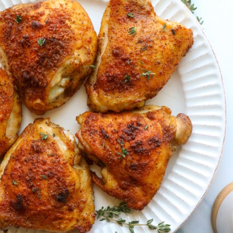 bone-in chicken thighs on a plate with fresh thyme