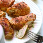 crispy bone in chicken thighs cut on a plate with a fork.