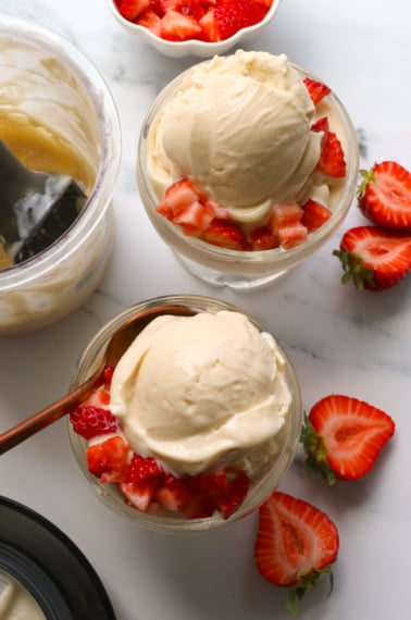 greek yogurt ice cream served in two bowls with strawberries.