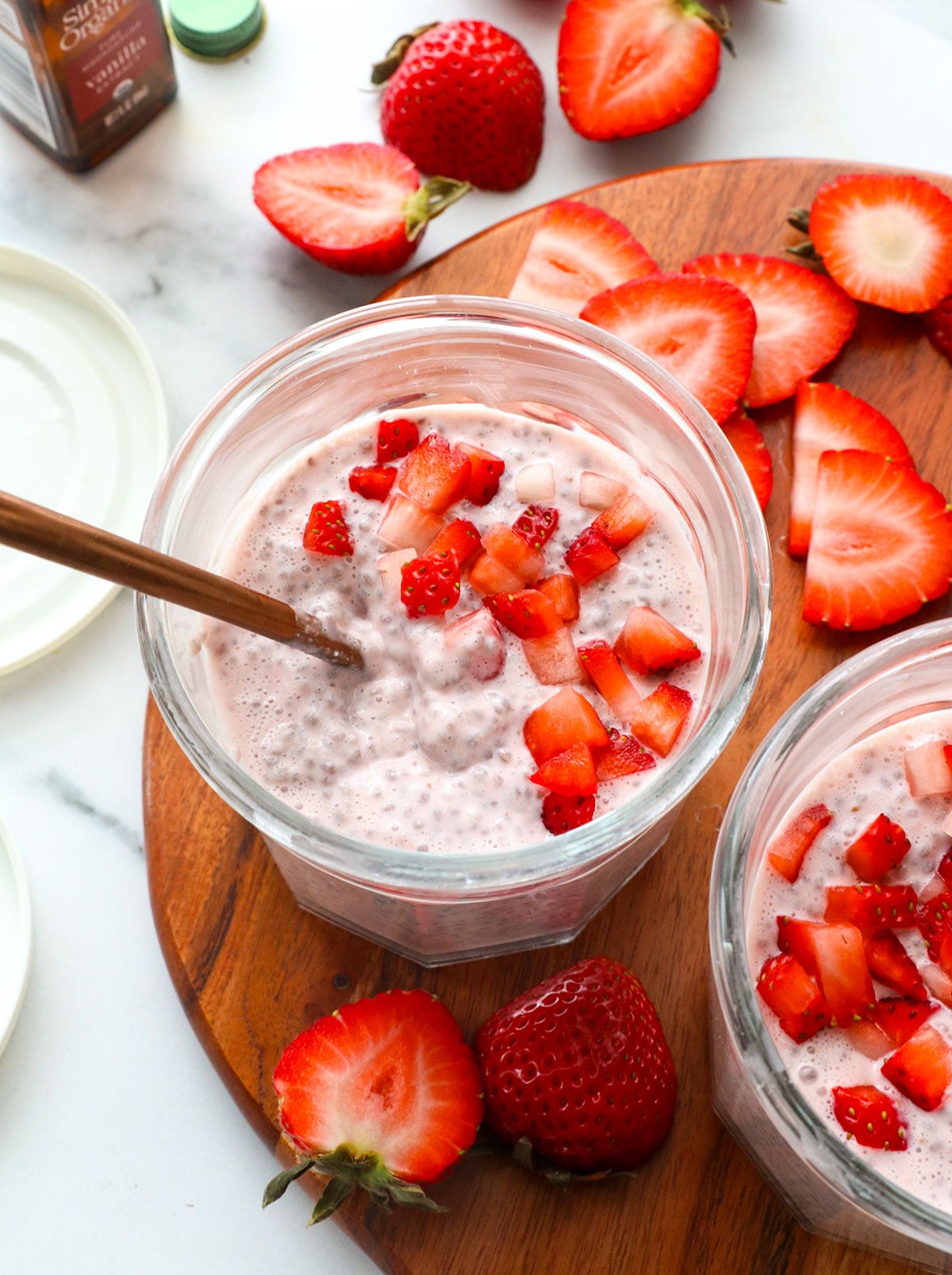 strawberry chia pudding in a glass jar with extra strawberries on top.