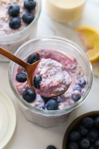 blueberry overnight oats lifted on a spoon.