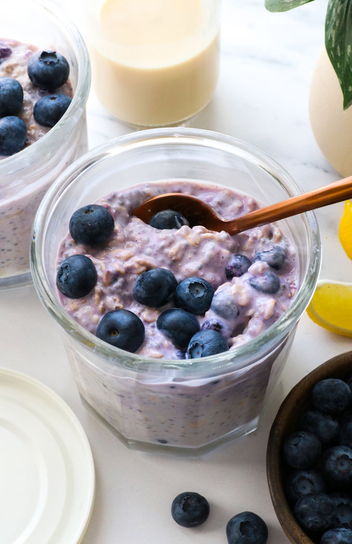 blueberries on a jar of overnight oats with a spoon.