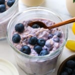 blueberries on a jar of overnight oats with a spoon.
