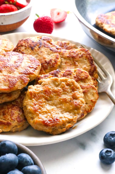 chicken breakfast sausage patties on a plate with berries nearby.