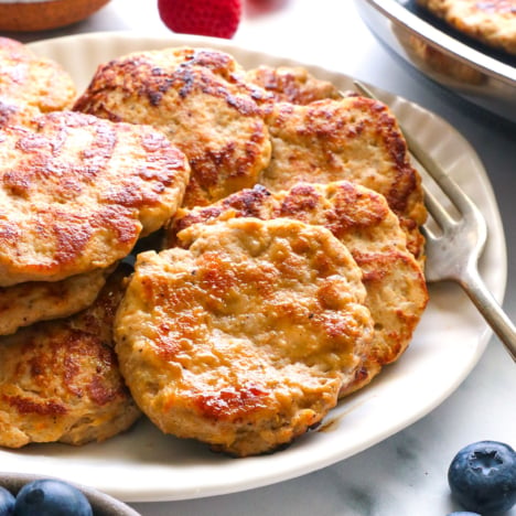 chicken breakfast sausage patties on a plate with berries nearby.