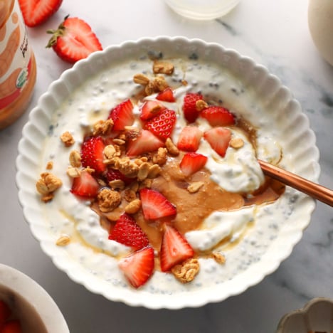 white bowl filled with greek yogurt, chia seeds, peanut butter, and fruit.